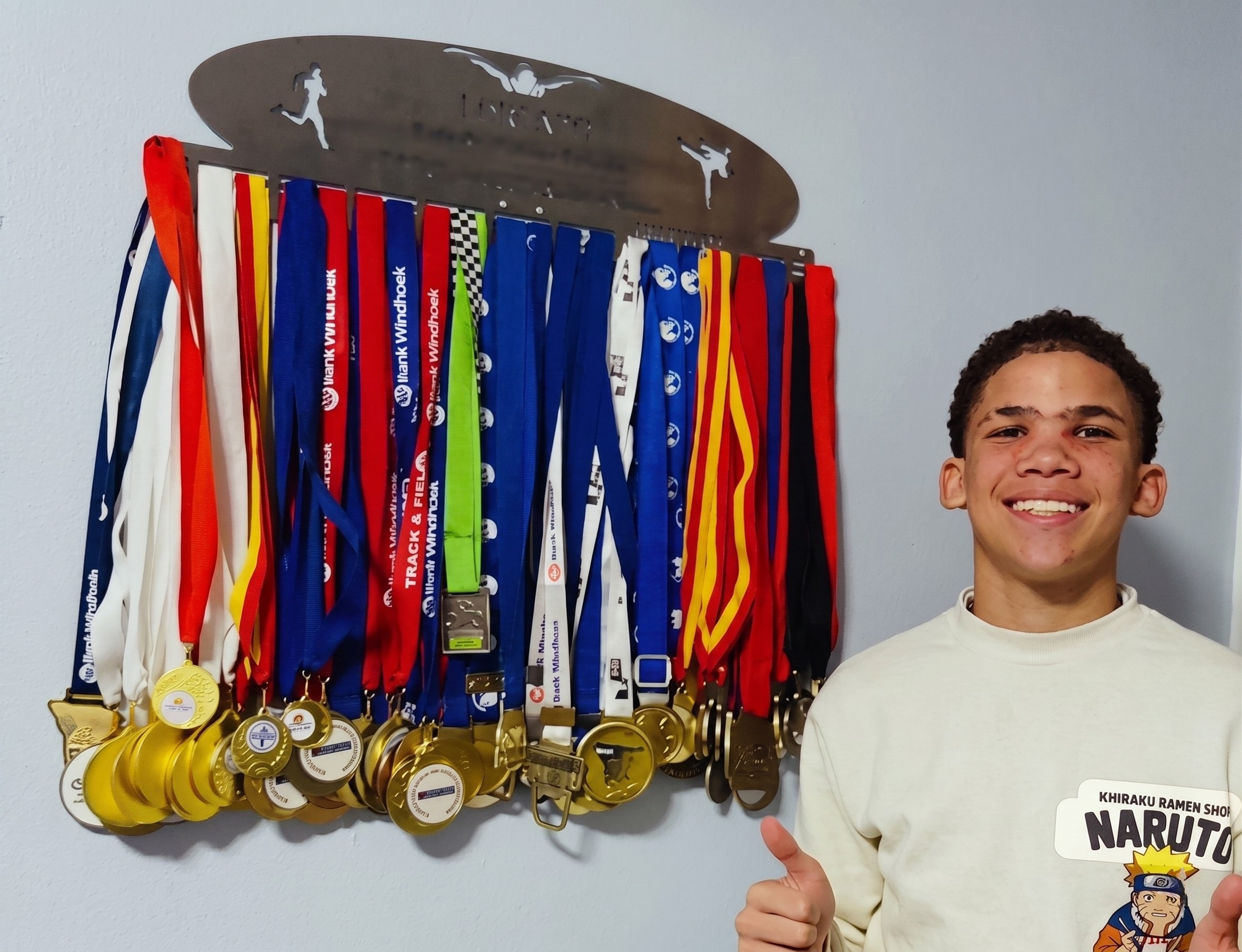 Lorenzo smiling next to his full medal collection