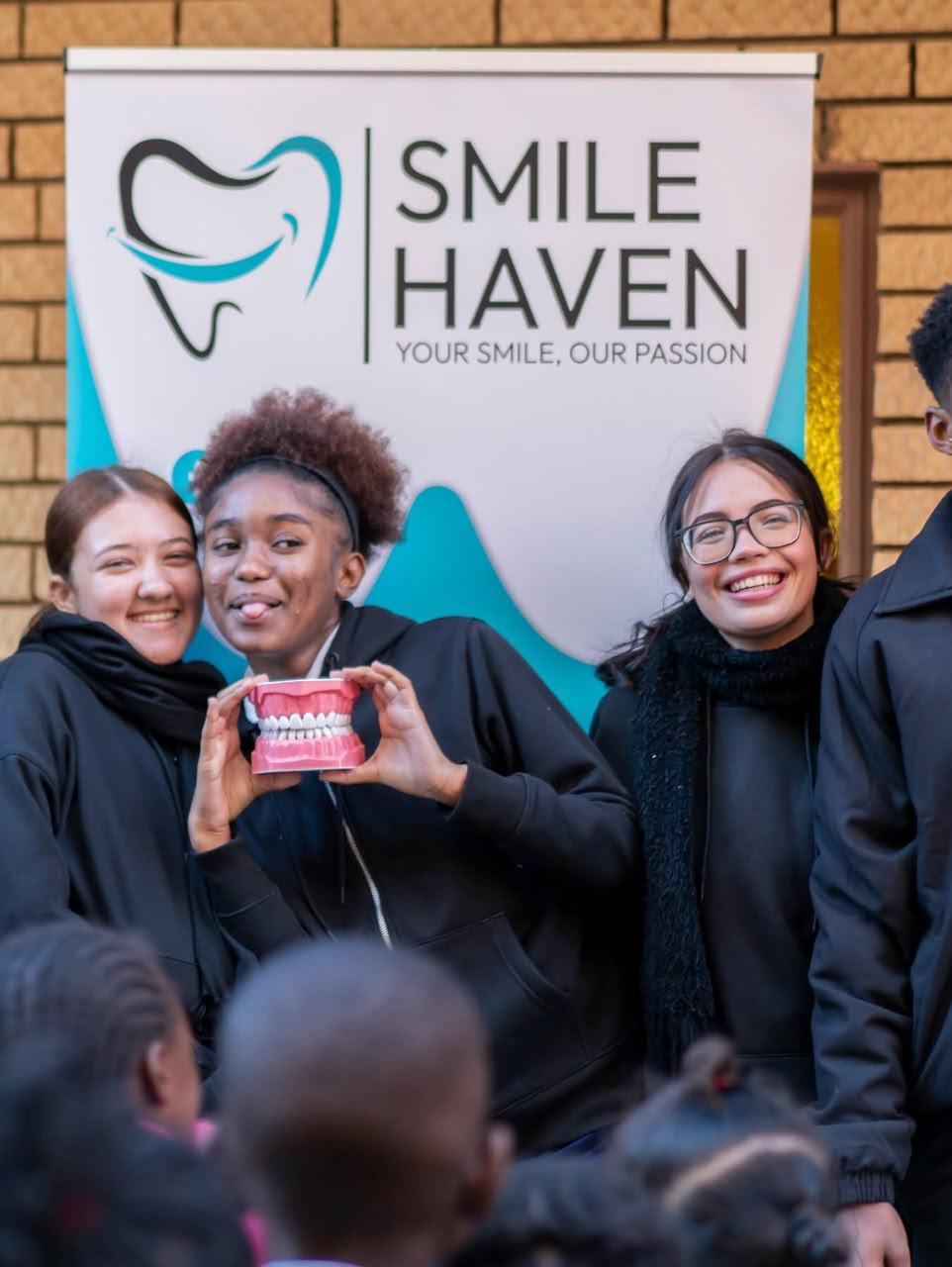 IA Academy learners holding a dental model at the Smile Haven visit, July 2026
